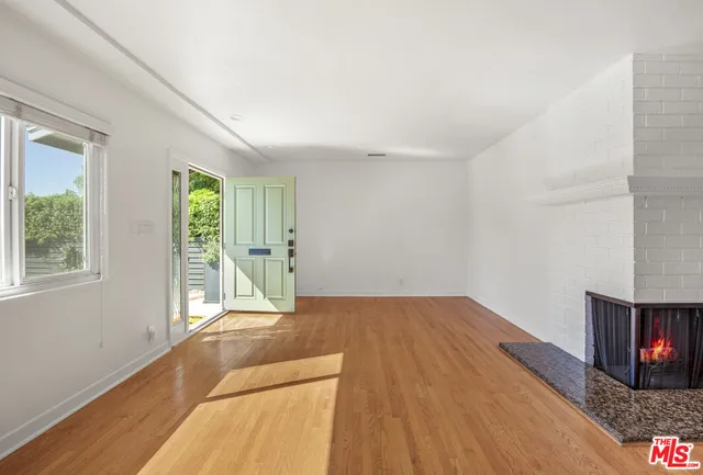 a view of a livingroom with wooden floor and a fireplace
