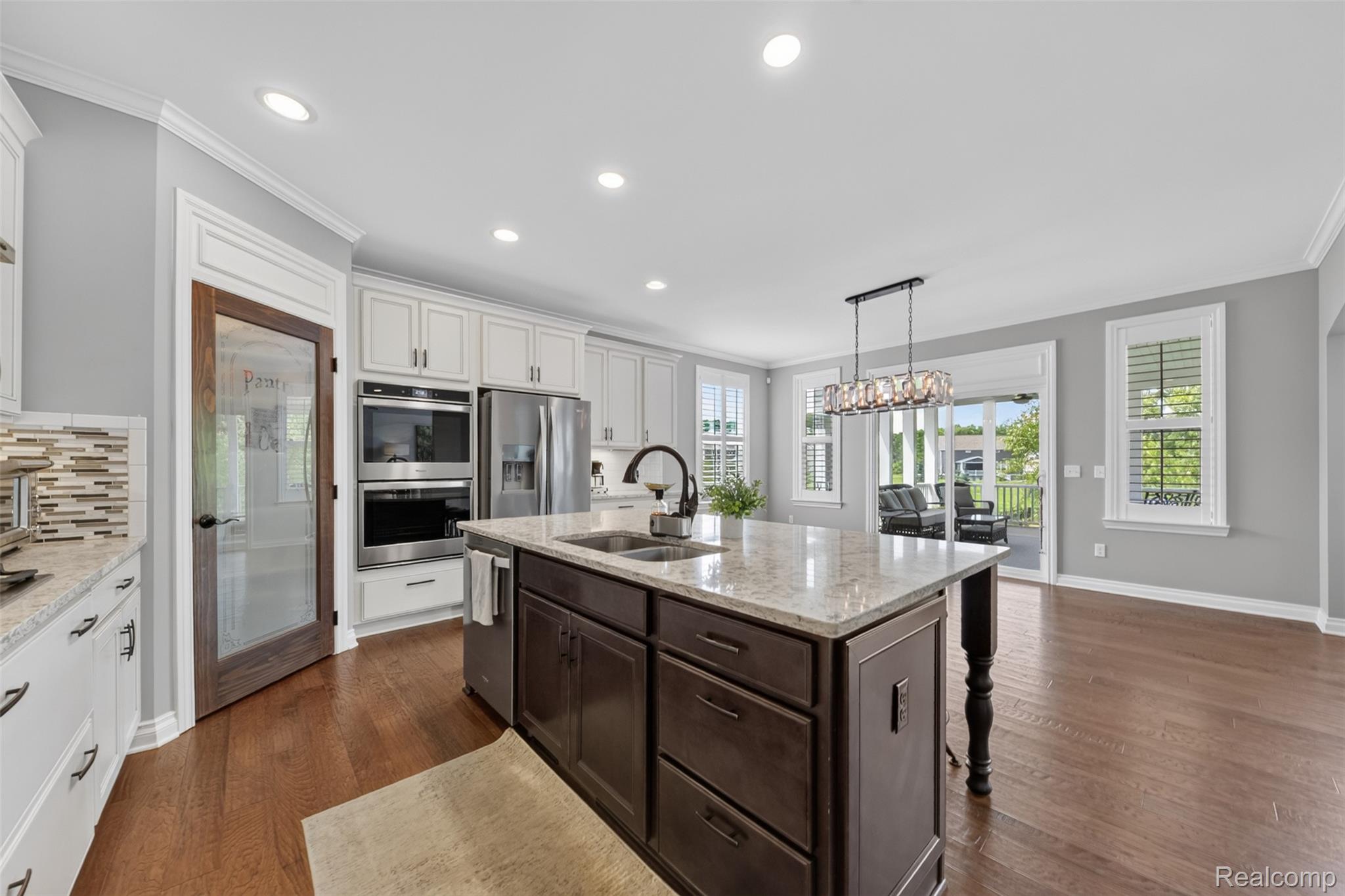 2531 Walnut View Drive Howell, MI 48855 - Photo 14 of 34 Gourmet kitchen featuring a central island with a stone countertop, built-in double ovens, stainless steel refrigerator, white shaker cabinetry, and wood-finish flooring