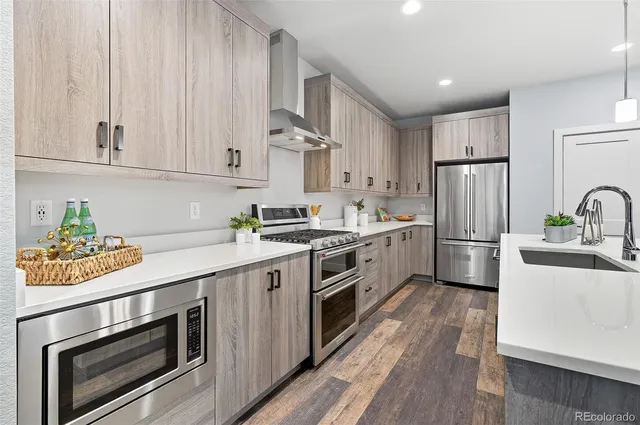 a large kitchen with lots of counter space a sink appliances and a living room view
