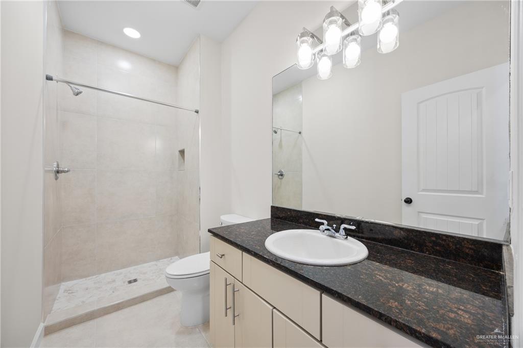 813 Travis Street, Unit 408 Mission, TX 78572 - Photo 15 of 25 a bathroom with a granite countertop sink a toilet a mirror and shower