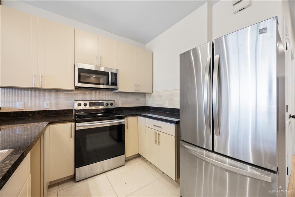 813 Travis Street, Unit 408 Mission, TX 78572 - Photo 7 of 25 a kitchen with stainless steel appliances granite countertop a refrigerator stove and microwave