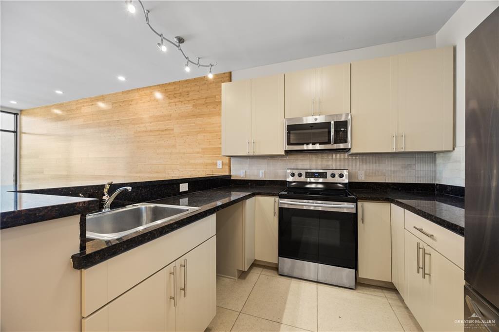 813 Travis Street, Unit 408 Mission, TX 78572 - Photo 8 of 25 a kitchen with granite countertop white cabinets sink and stainless steel appliances