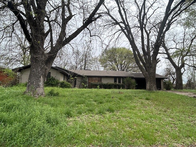 a view of house in front of a big yard with large trees