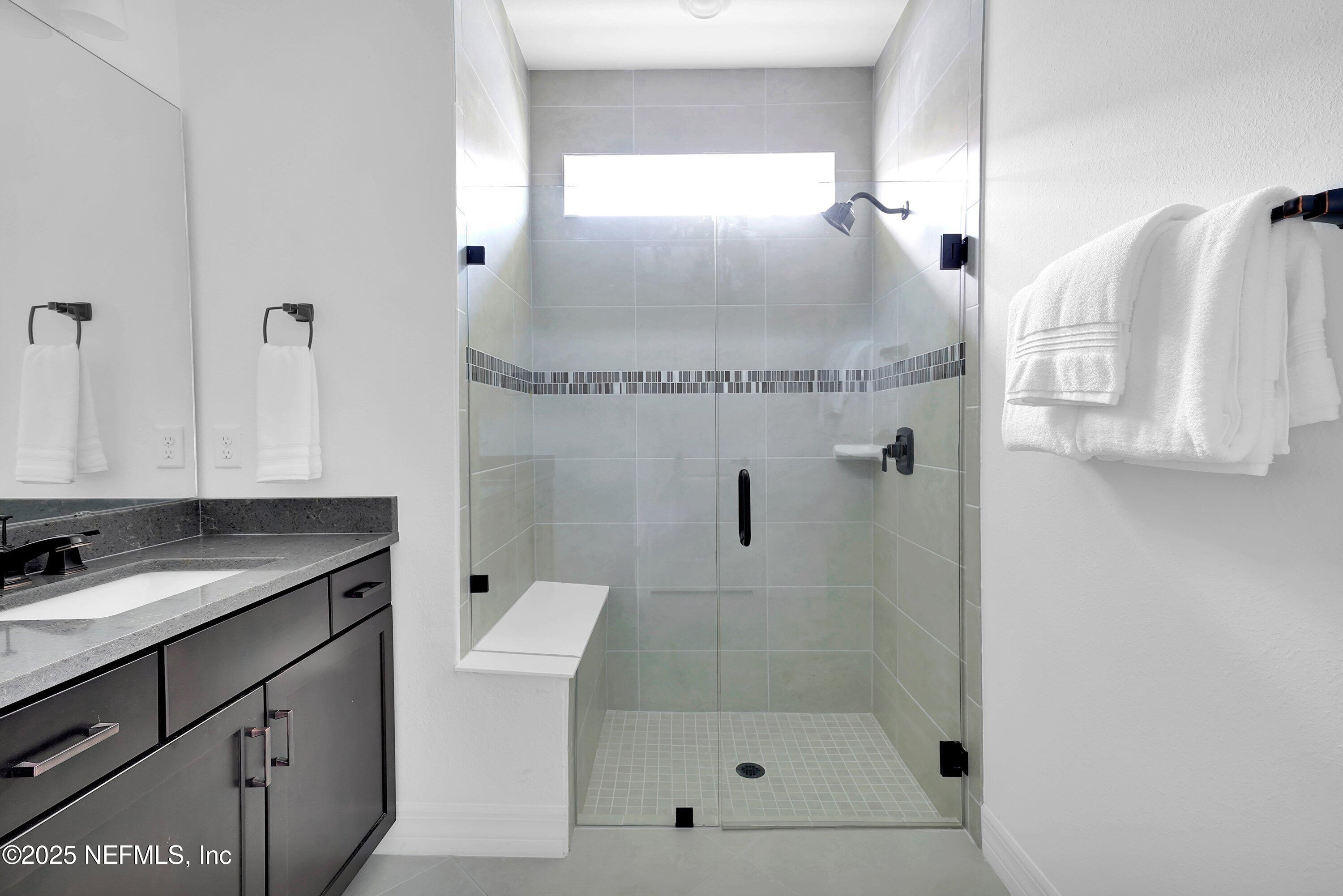 918 Floco Avenue Yulee, FL 32097 - Photo 13 of 37 a bathroom with a granite countertop sink a mirror and shower