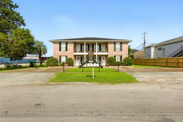 a view of house in front of a big yard with large trees