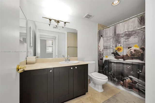 a bathroom with a granite countertop sink a toilet a mirror and shower