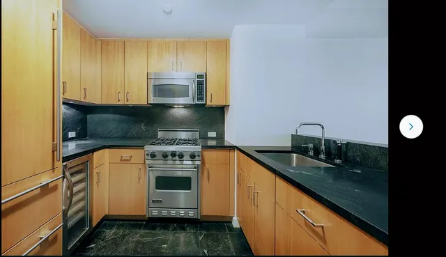 a kitchen with granite countertop a sink stainless steel appliances and cabinets