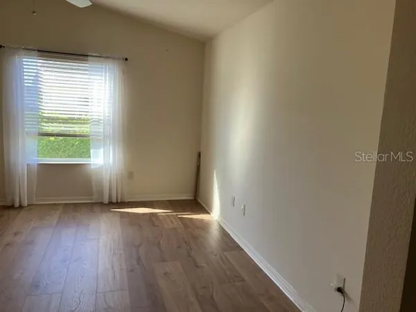 an empty room with wooden floor and windows