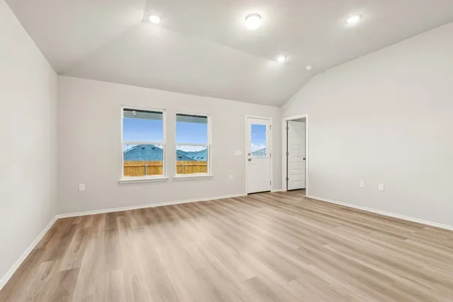 an empty room with a window and a wooden floor
