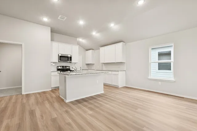 a kitchen with white cabinets and appliances
