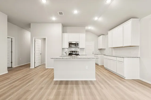 a kitchen with stainless steel appliances granite countertop a stove a sink and a refrigerator