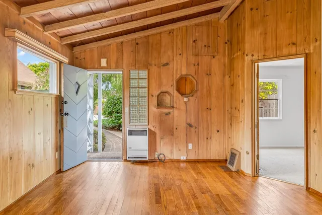 a view of an empty room with wooden floor and a window