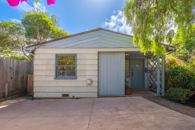 a small white house with a small yard and wooden fence