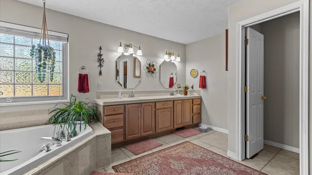 a bathroom with a granite countertop tub a double vanity sink and mirror