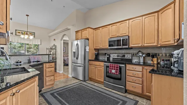 a kitchen with stainless steel appliances granite countertop a refrigerator stove and sink