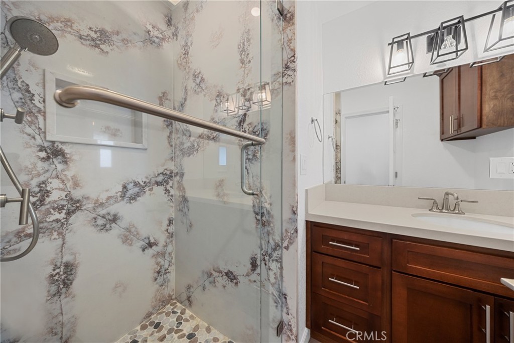 12646 10th Street Yucaipa, CA 92399 - Photo 31 of 72 a bathroom with a granite countertop sink a mirror and shower