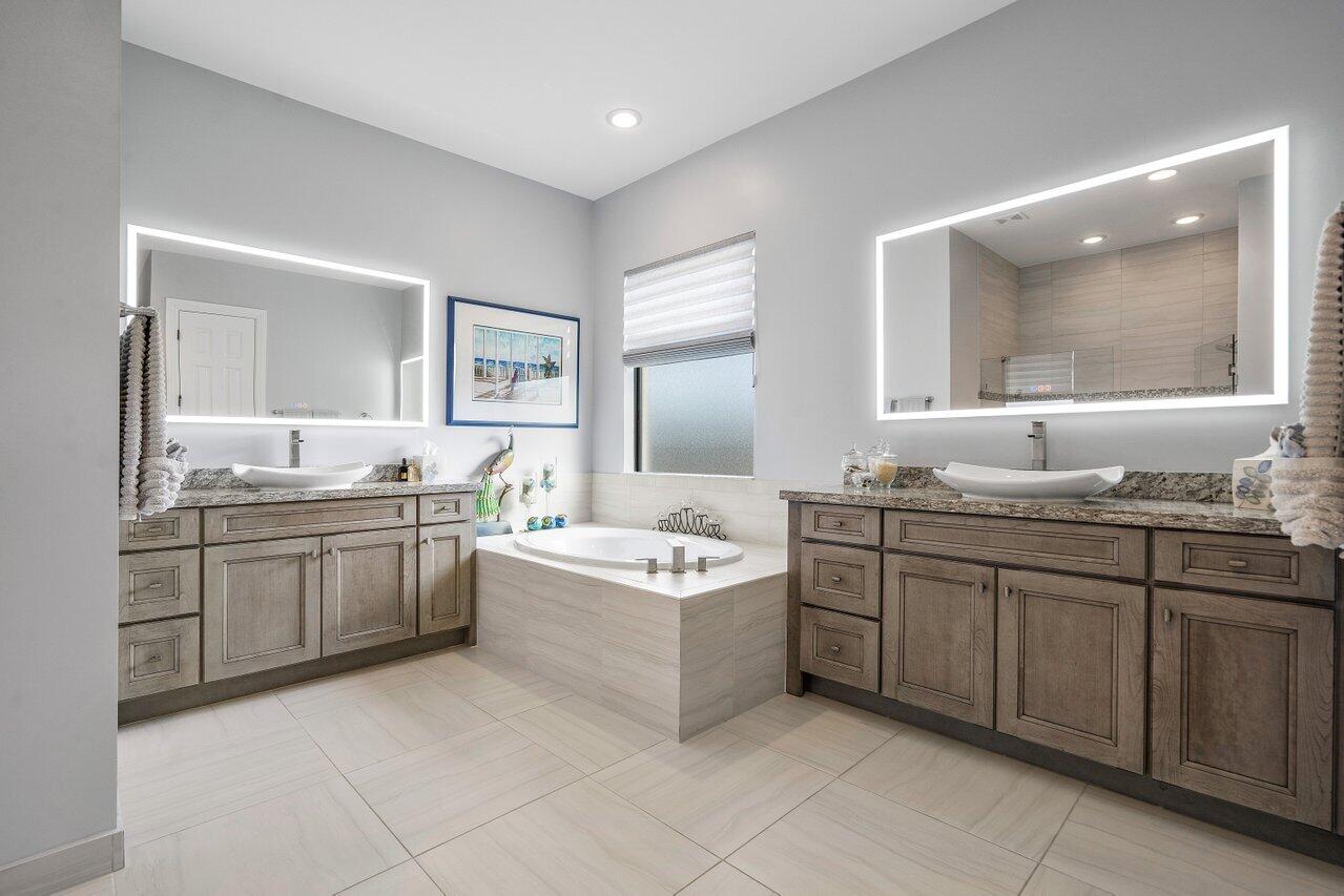 11792 Leon Circle Parkland, FL 33076 - Photo 15 of 51 a bathroom with a granite countertop double vanity sink a mirror and a bathtub