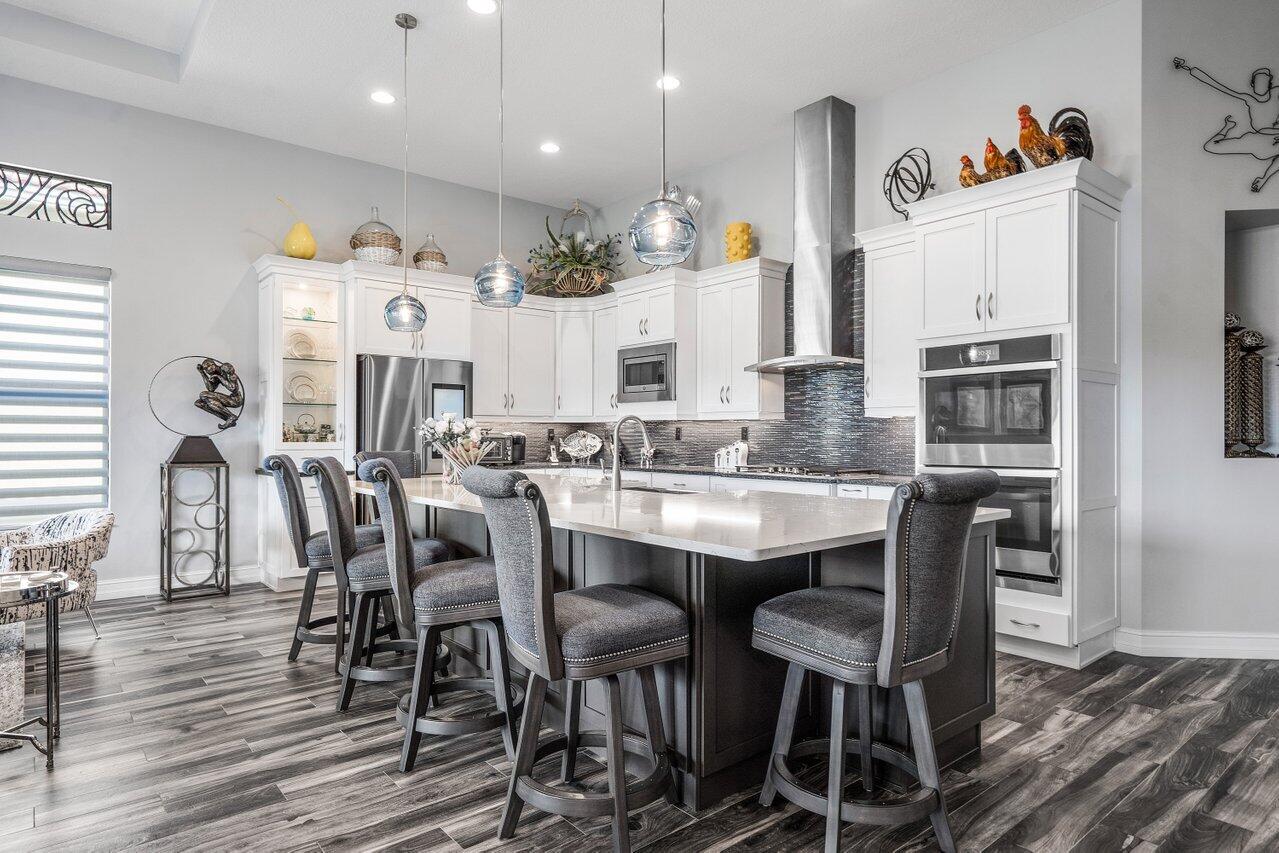 11792 Leon Circle Parkland, FL 33076 - Photo 7 of 51 a kitchen with stainless steel appliances granite countertop a dining table chairs stove refrigerator and cabinets