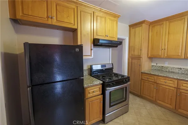a kitchen with stainless steel appliances granite countertop a refrigerator a stove and a sink