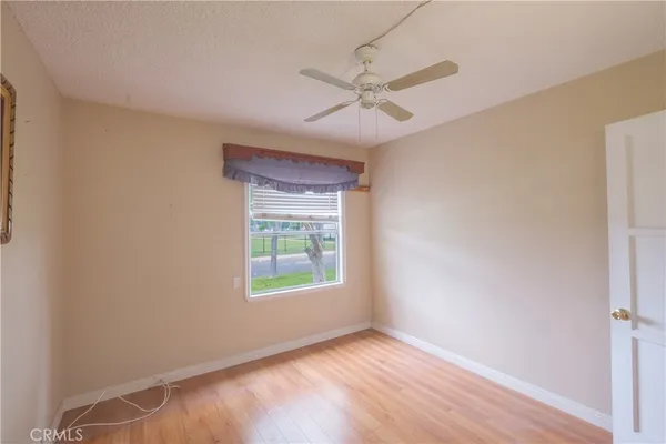 an empty room with wooden floor fan and windows