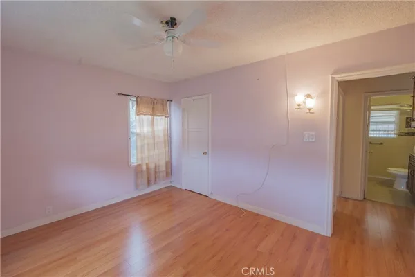 a view of empty room with wooden floor and fan