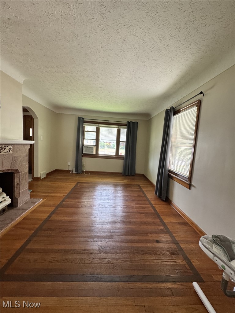 3712 Snow Road Cleveland, OH 44134 - Photo 12 of 40 Unfurnished living room featuring arched walkways, a fireplace, a textured ceiling, and wood-type flooring