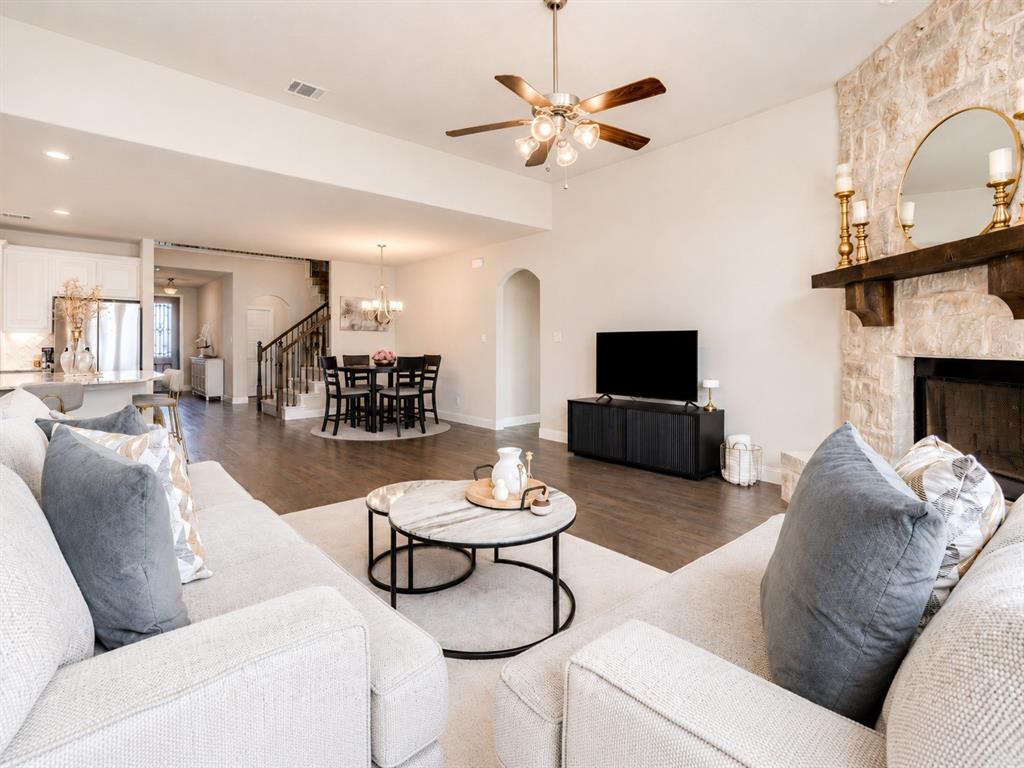 25 Morrison Road Howe, TX 75459 - Photo 4 of 27 Spacious interior featuring a stone fireplace with a wood-beam mantel, wood-finish flooring, and a ceiling fan with integrated lighting