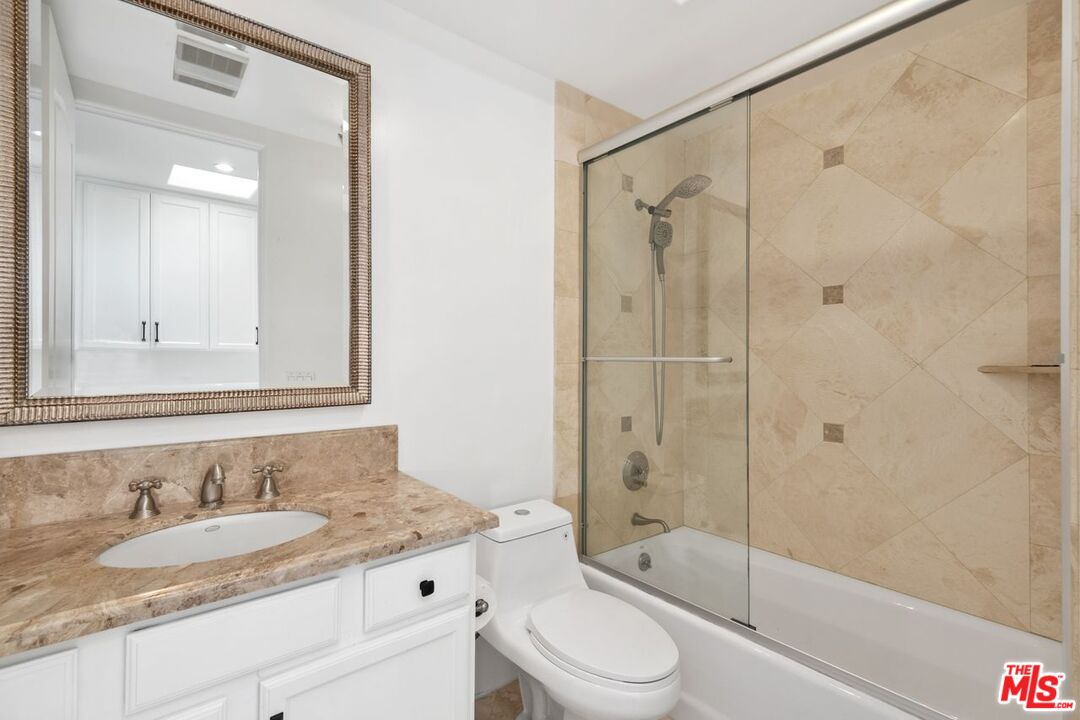 11974 Mayfield Avenue, Unit 2 Los Angeles, CA 90049 - Photo 12 of 26 a bathroom with a granite countertop sink a toilet and shower