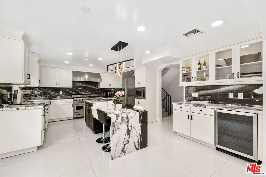 11974 Mayfield Avenue, Unit 2 Los Angeles, CA 90049 - Photo 21 of 26 a kitchen with white cabinets and stainless steel appliances