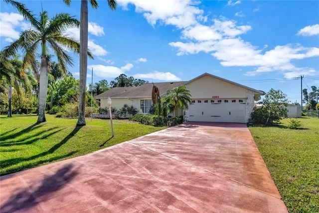 a view of a house with a yard and palm trees