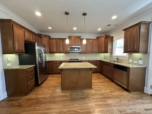 a large kitchen with kitchen island granite countertop wooden cabinets a refrigerator and a sink