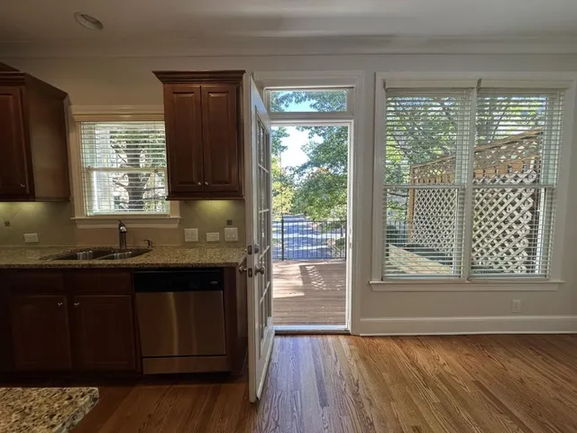 a kitchen with granite countertop a sink wooden floor and a large window
