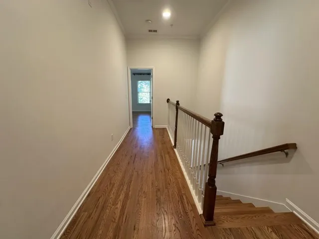 a view of a hallway with wooden floor and staircase