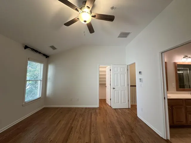 an empty room with wooden floor closet and windows