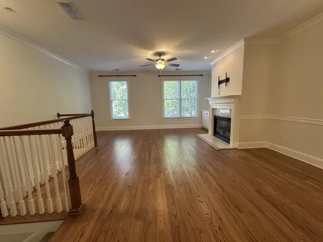 an empty room with wooden floor fireplace and windows