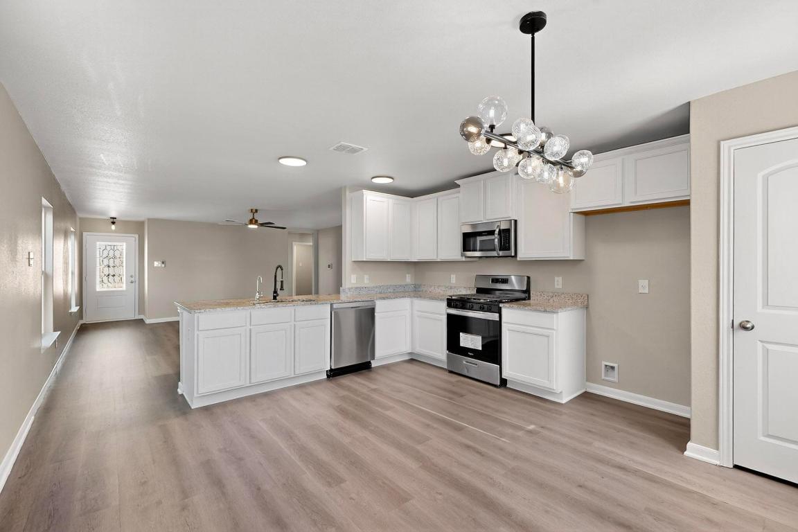 606 Aplite Pass Maxwell, TX 78656 - Photo 11 of 30 Kitchen featuring appliances with stainless steel finishes, a peninsula, white cabinetry, ceiling fan, and light wood finished floors