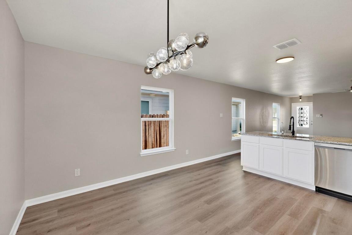 606 Aplite Pass Maxwell, TX 78656 - Photo 13 of 30 Kitchen with white cabinets, stainless steel dishwasher, hanging light fixtures, and light wood-style flooring