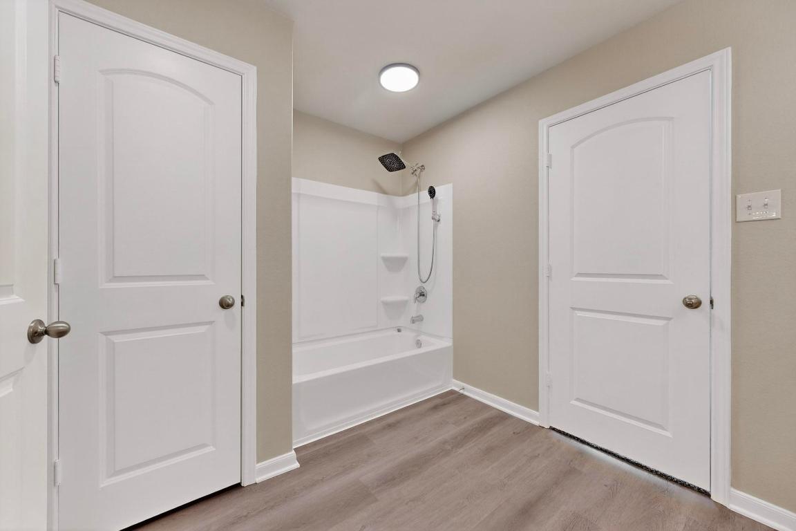 606 Aplite Pass Maxwell, TX 78656 - Photo 25 of 30 Bathroom featuring shower combination and light wood-style flooring