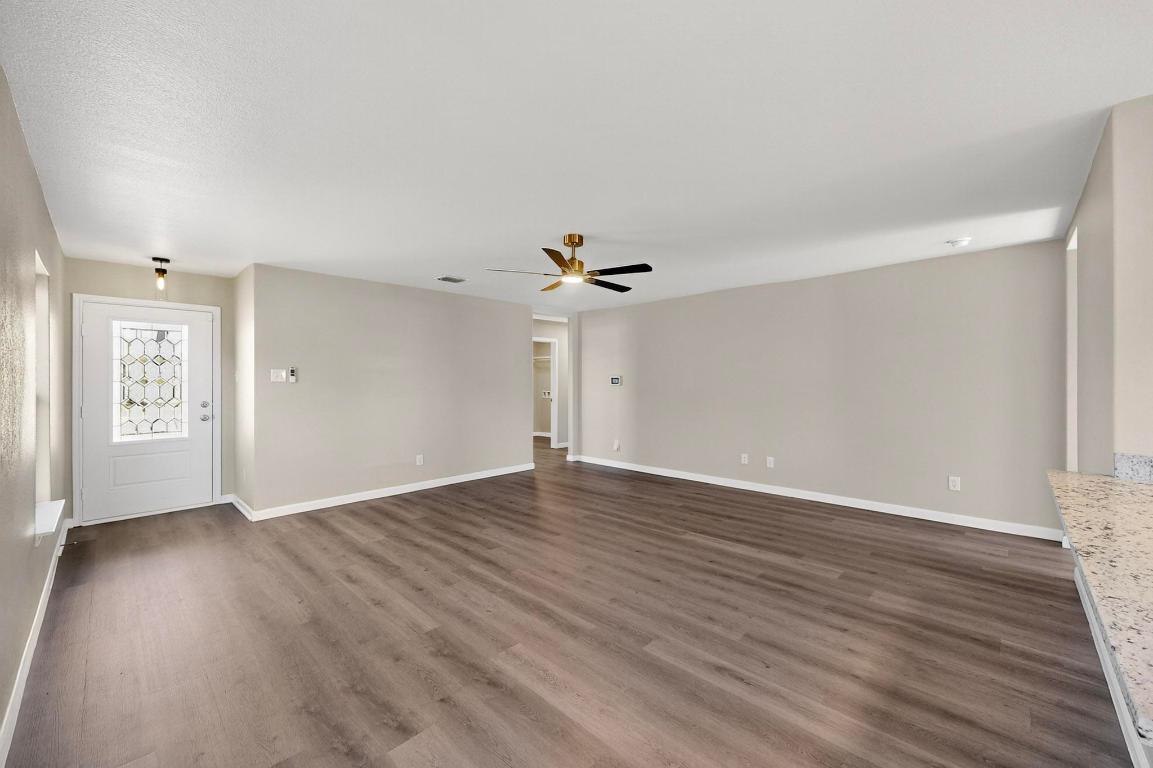 606 Aplite Pass Maxwell, TX 78656 - Photo 4 of 30 Unfurnished living room with dark wood finished floors and a ceiling fan