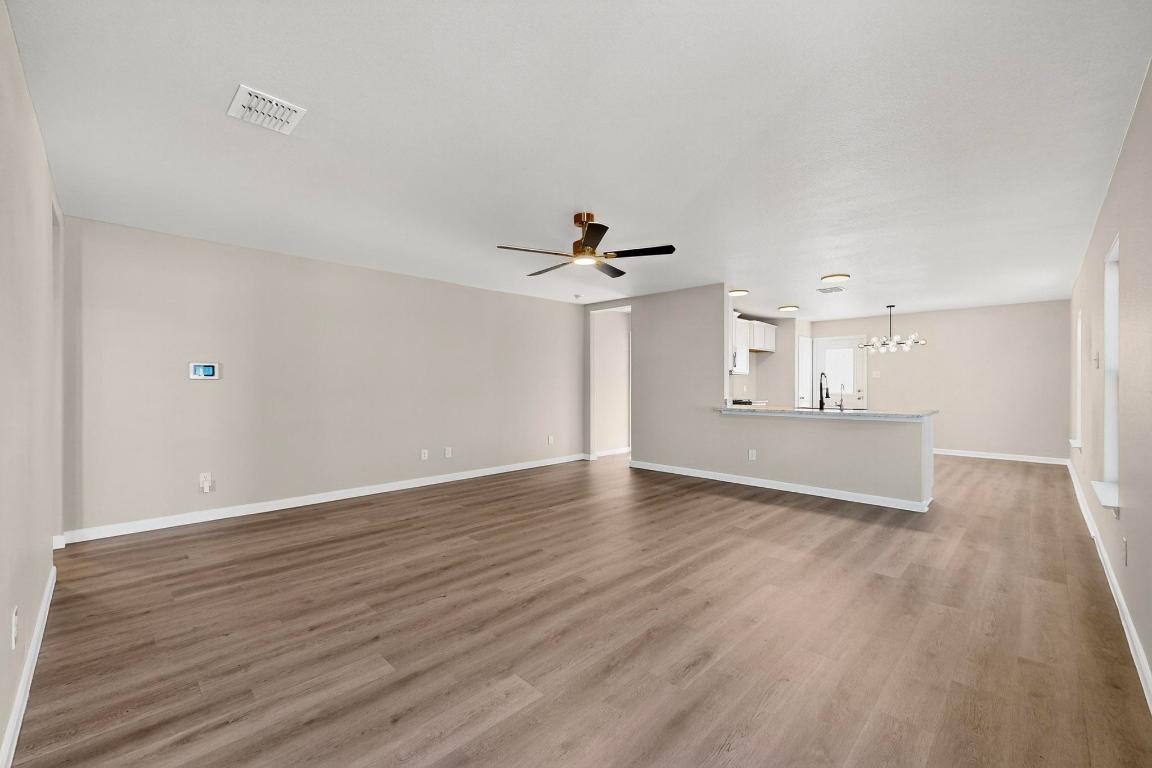 606 Aplite Pass Maxwell, TX 78656 - Photo 7 of 30 Unfurnished living room with light wood-type flooring, a ceiling fan, and a chandelier