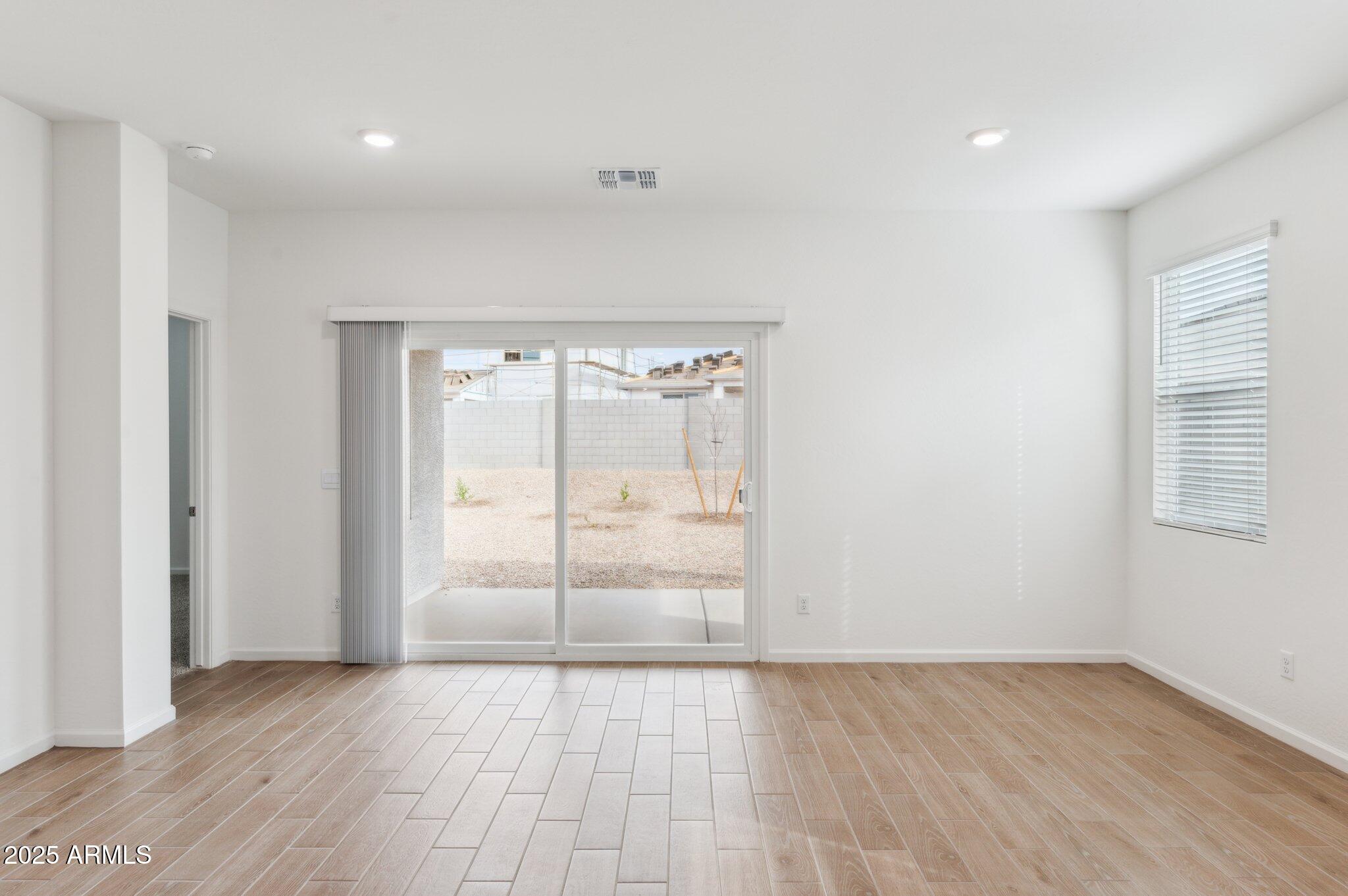 25464 West Fraktur Road Buckeye, AZ 85326 - Photo 2 of 19 an empty room with wooden floor and windows