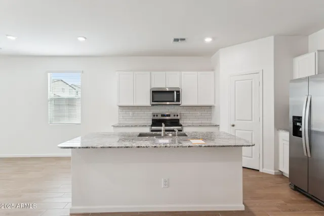 a kitchen with kitchen island granite countertop a stove top oven a sink and a granite counter tops