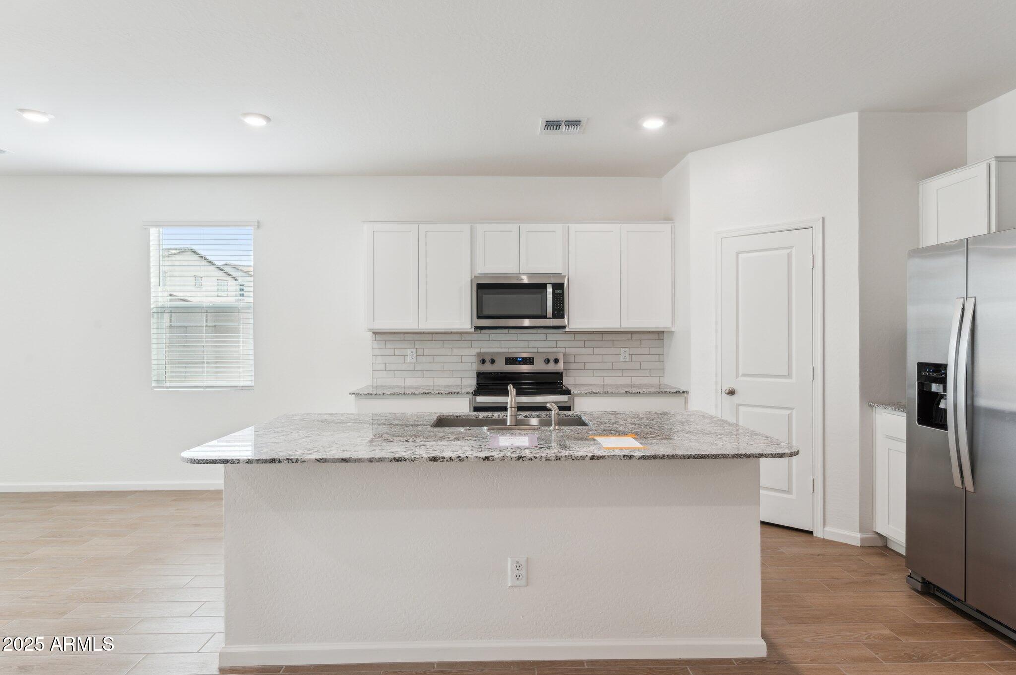25464 West Fraktur Road Buckeye, AZ 85326 - Photo 5 of 19 a kitchen with kitchen island granite countertop a stove top oven a sink and a granite counter tops
