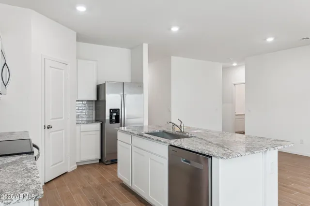 a kitchen with stainless steel appliances granite countertop a sink and a refrigerator