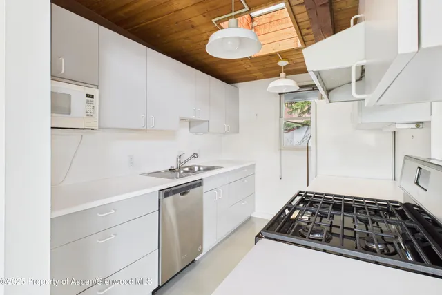 a kitchen with stainless steel appliances a stove a sink and white cabinets