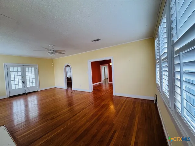 a view of empty room with wooden floor and fan