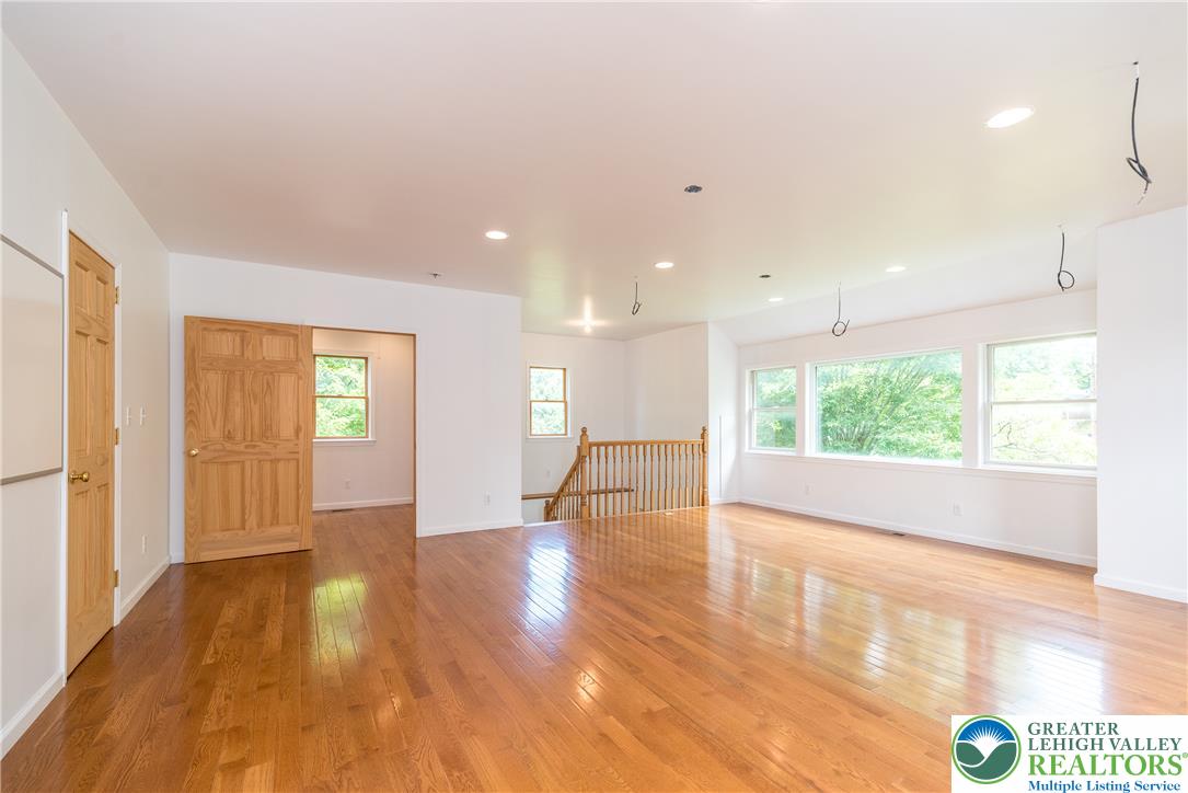 1815 Leithsville Road Hellertown, PA 18055 - Photo 17 of 38 Hardwood floors reflect natural light throughout this spacious, open-plan living area with ample windows and a prominent staircase.