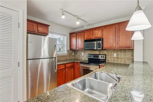 a kitchen with stainless steel appliances granite countertop a refrigerator stove top oven a sink and dishwasher
