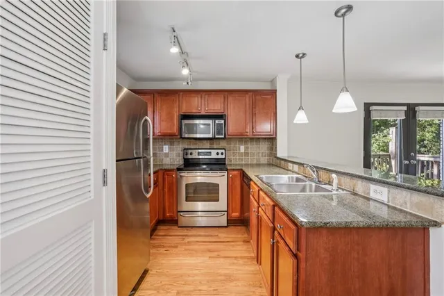 a kitchen with stainless steel appliances granite countertop a sink a stove and a refrigerator