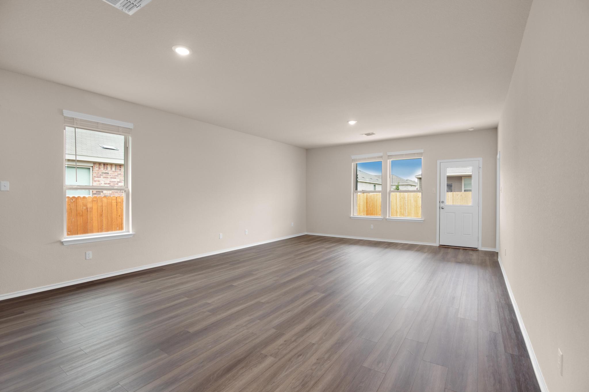 200 Janice Road Taylor, TX 76574 - Photo 6 of 25 A spacious, airy room with rich hardwood-style flooring and multiple windows framing neighborhood views.